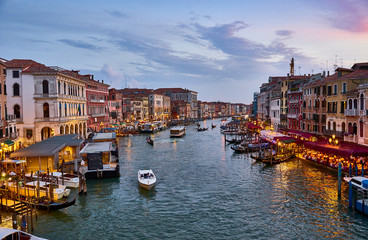 Fototapeta na wymiar Canal Grande with boats and lights in Venice at Sunset. Next to famous Rialto Bridge and the Street 