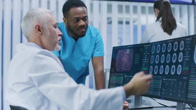 Medical Scientist and Surgeon Discussing CT / MRI Brain Scan Images on a Personal Computer in Laboratory.  Shot on RED EPIC-W 8K Helium Cinema Camera.
