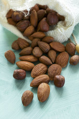 Almonds pour from sackcloth on turquoise wooden background