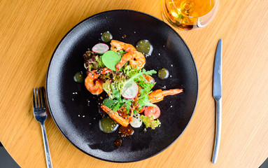 Appetizing spicy salad with shrimps, radish and sauce on the tab