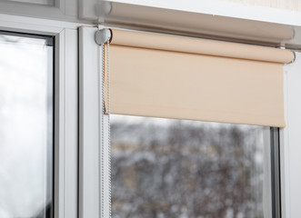Beige blackout roller blind on the white plastic window. Shutters on the plastic window.