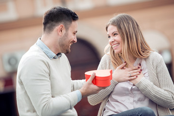 Smiling boy giving to his girlfriend a gift