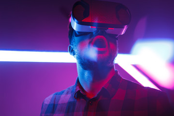 Shocked man in VR goggles in nightclub