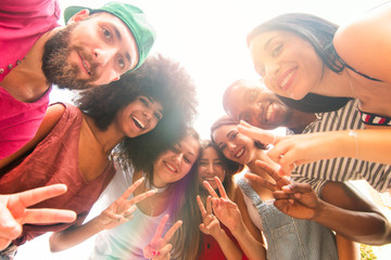 group of friends in a circle having fun. cheerful university students taking photo together smiling and gesturing peace sign.