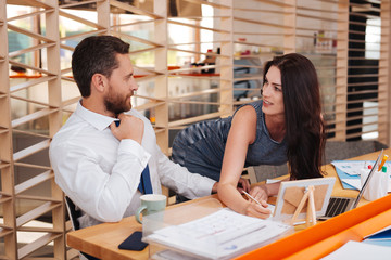 Feeling excited. Content dark-haired woman seducing her boss while standing at his table