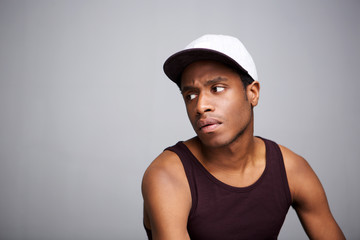 cool african guy holding with cap against gray background