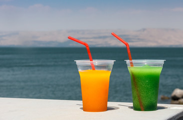 Cool fresh juices on a background of blue sea, sky and mountain