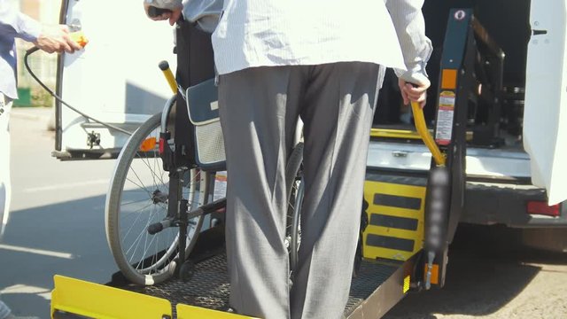 Lifting equipment for people with disabilities in the minivan - man in the wheelchair climb down from minivan