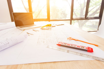 Architectural plan, laptop, dividers ,pencil ,pen ,ruler, glasses and smartphone and blueprint on wooden table.