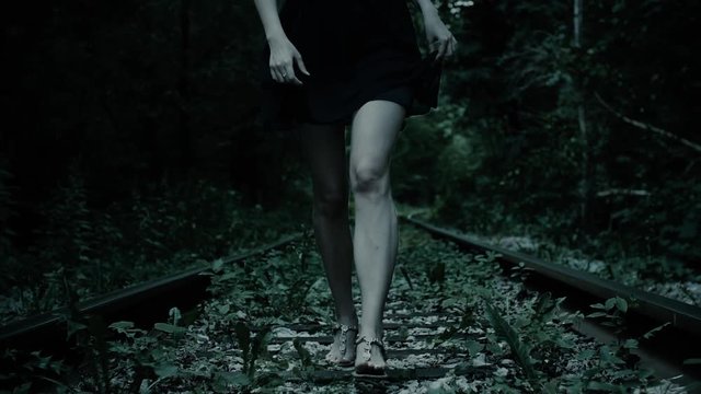 Night, fleeing legs frightened girl. Railway track in forest.