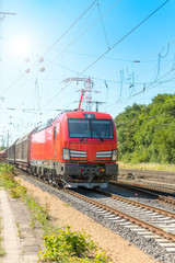 Fototapeta na wymiar Güterzug mit einer modernen Lokomotive mit Sonne