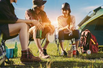 Asian friends group travel camping together in forest with backpack and tent picnic drinks beer,water at nature outdoor young teenager talking relax,rest near mountain view.