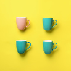 Pattern from blue and pink cups over yellow background. Square crop. Birthday party celebration, baby shower concept. Punchy pastel colors. Minimalist style design