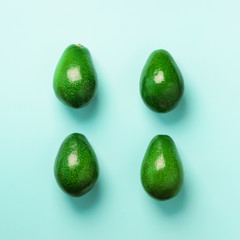 Green avocado pattern on blue background. Top view. Pop art design, creative summer food concept. Organic avocadoes in minimal flat lay style. Square crop