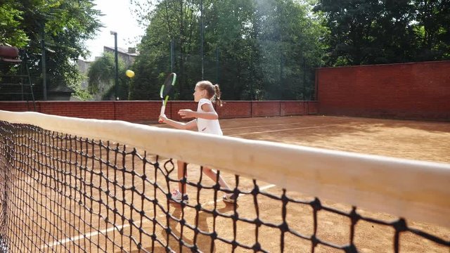 Coacher teaching young girl to playing tennis.