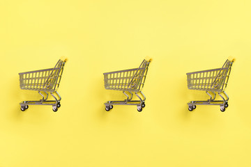 Shopping cart on yellow background. Minimalism style. Creative design. Top view with copy space....