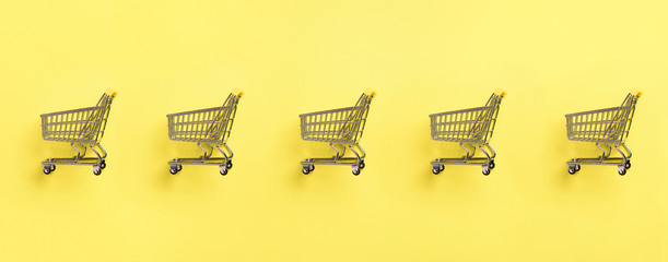 Shopping cart on yellow background. Minimalism style. Creative design. Top view with copy space....
