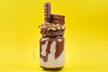 Chocolate extreme milkshake with brownie cake, chocolate paste and sweets. Crazy freakshake food trend. Copy space