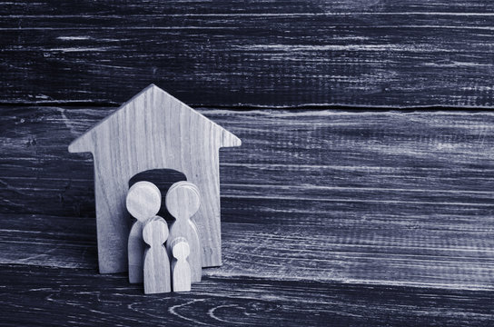 Two Wooden Figures Of People Are Standing Near The Entrance To The Wooden House. The Concept Is Protective And Defense. Bouncers, Burglars. Protection Of Private Property, Protection.