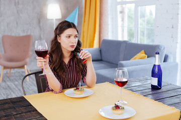 Bad memories. Dark-haired appealing woman with long wavy hair having bad memories about her last birthday