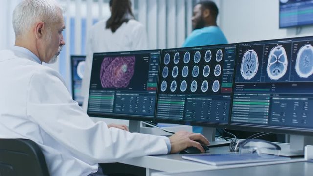 Experienced Senior Scientist Working with CT/ MRI Brain Scan Images on a Personal Computer in Laboratory. Neurologists / Neuroscientists in Medical Research Center.