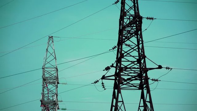 Two large electronic pillars of steel are on the background of the sky, then the camera is lowered and they are standing on the background of bushes of grass and wood , they hang wires. LEP