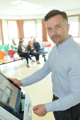 Fototapeta premium man using electronic kiosk in hospital waiting room
