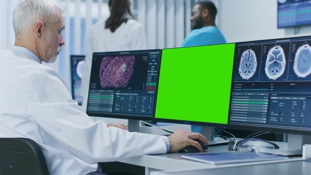 Scientist Working with Mock-up Green Screen and CT Brain Scan Images on a Personal Computer in Laboratory. Neuroglogists work in Neuroscience Medical Research Center. 