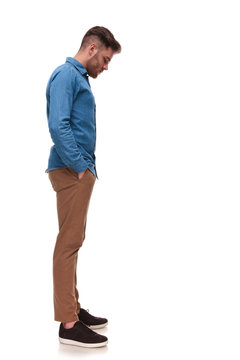 young casual man waiting in line looks down at something