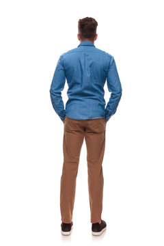 rear view of casual man standing with hands in pockets