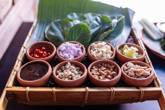 Thai appetizer called "Miang Kham", some of nutritious snack wrapped in leaves with a sweet and salty sauce.