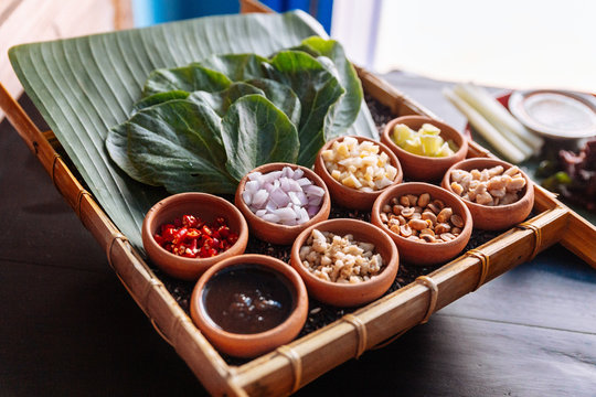 Thai appetizer called "Miang Kham", some of nutritious snack wrapped in leaves with a sweet and salty sauce.