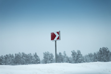 Red arrow signs in a snow. A forest on the background