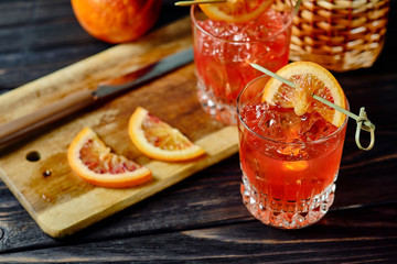 Two glasses of cocktails with slices of Sicilian orange on wooden plate with knife. Horizontal...