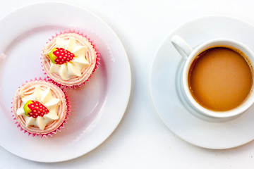Obraz na płótnie Canvas A plan view of strawberry and cream cupcakes and white cup and plate with coffee