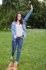 Lady waving while walking dog