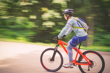 A cyclist in a helmet rides a bicycle path, motion blur