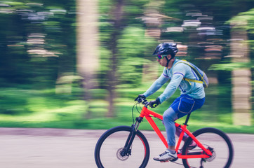 Fototapeta premium A cyclist in a helmet rides a bicycle path, motion blur
