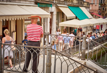 Fototapeta na wymiar Typical Venetian gondolier in traditional clothing is waiting for customers