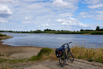Obraz premium packed touring bike during break on a river bank