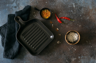 Empty ceramic pan and seasonings on dark grunge background