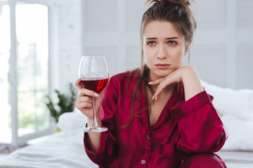 Feeling terrible. Green-eyed woman wearing dark-red pajama feeling simply terrible after breakup
