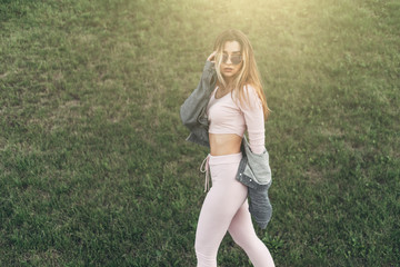 Portrait of Young and Beautiful Woman in Casual Clothes in the Street. Dressed in Pink Shirt and Pants. Spring, Summer Concept. Relax Time. Girl with Sunglasses. Enjoy City Sunset.