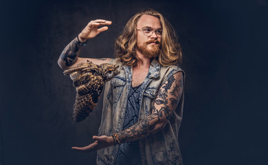Portrait of a tattoed redhead hipster male with long luxuriant hair and full beard dressed in a...