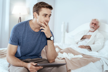 Buy online. Pensive man carrying tablet and senior man posing on bed