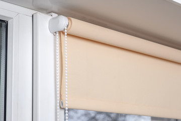 Beige blackout roller blind on the white plastic window. Shutters on the plastic window.