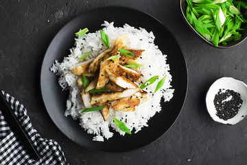 Rice chicken breast bowl with spring green onions and herbs