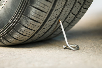 nail on an asphalt road with a car.