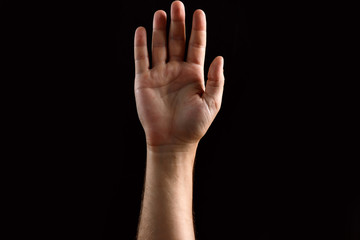 Male palm raised up, isolated on a dark background. Isolate