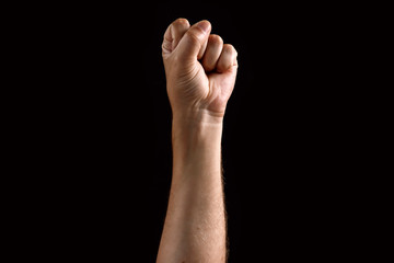 Male fist raised up, isolated on a dark background. Isolate